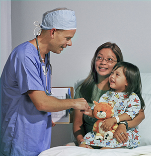 Healthcare provider talking with little girl and woman in hospital room.