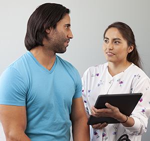 Health care provider talking to man in exam room.