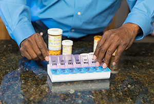 Person taking pill out of pill organizer.