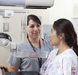Healthcare provider positioning woman for mammogram.