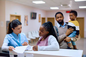 Parent checking in with nurse, other parent holding child.