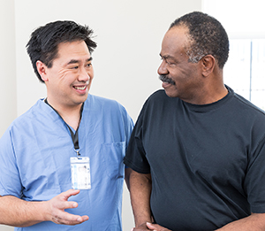 Health care provider talking to man in exam room.
