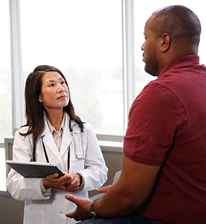 Man in exam room talking to healthcare provider.