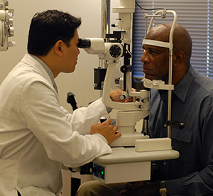 Healthcare provider examining man's eyes.