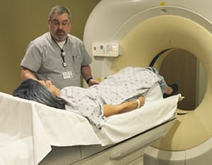 Technician preparing person for CT scan.