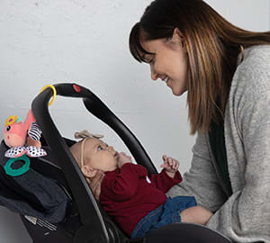 Person placing baby in infant carrier.