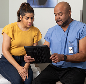 Healthcare provider and woman looking at electronic tablet in exam room.