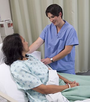 Health care provider talking to patient in hospital bed.