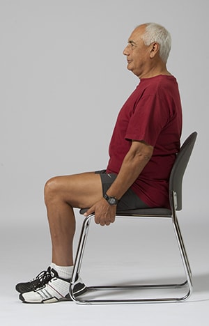 Person sitting in chair, holding the edges of the seat.