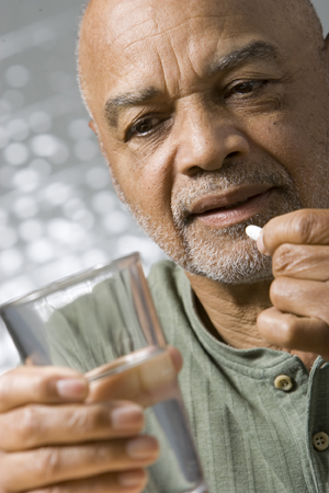 Man holding glass of water, preparing to take pill.