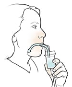 Woman inhaling medicine from nebulizer with mouthpiece.