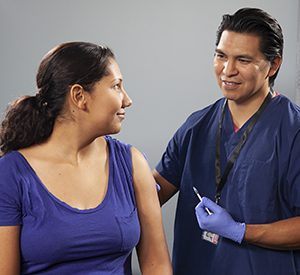 Healthcare provider giving woman injection in arm.