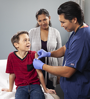 Healthcare provider giving boy injection in arm.