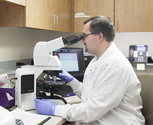Lab technician looking through microscope.